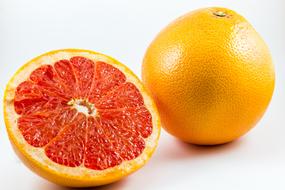 whole grapefruit and half of it on a white background