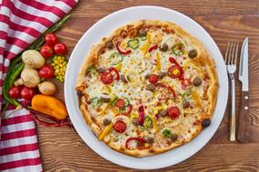 Colorful Italian vegetarian pizza served on a plate with on the table with vegetables