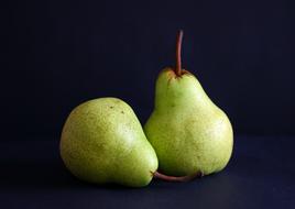photo of two green pears on a dark background