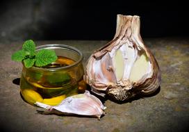 Closeup photo of Garlic head near jar with cloves in Oil