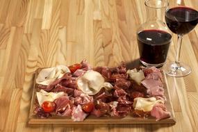 cold cuts on a board and a glass of red wine in a restaurant