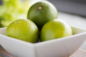 three limes in a white bowl