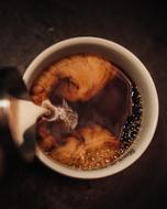 pour milk into hot coffee