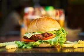 hamburger with green salad and french fries at blurred background