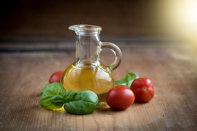 tomatoes, basil and olive oil in a transparent bottle