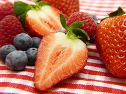 Strawberries. raspberries and blueberries on the red and white cloth