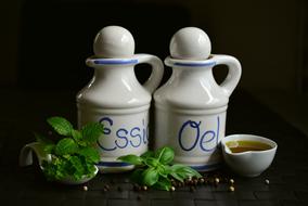 oil and vinegar in ceramic jugs and green basil