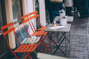 vintage Chairs and Tables on pavement at wall, open air cafe