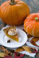 pumpkin pie on a plate and orange pumpkins on the table