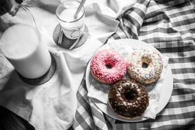 three multi-colored donuts and a glass of milk on the table