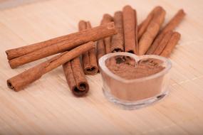 ground cinnamon in the shape of a heart and cinnamon sticks