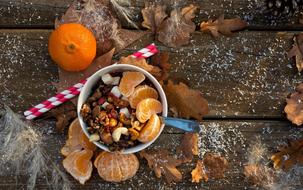 top view of granola with tangerine, autumn leaves and snow on the table