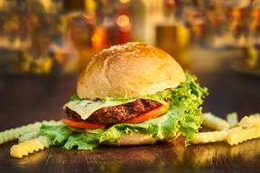 photo of a burger with greens and french fries on a table