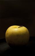 photo of a yellow apple in the dark