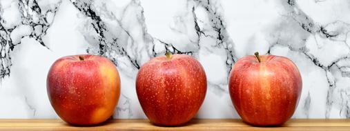 three red apples on a marble wall background