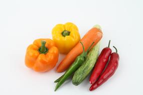 multi-colored peppers, carrots and zucchini on a white table