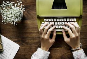 female hands on typewriter and flowers