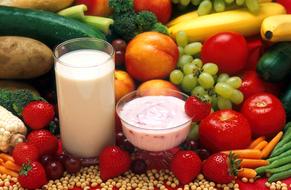 a glass of milk and yogurt on a background of ripe vegetables and fruits