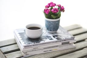 flowers and coffee on a stack of magazines