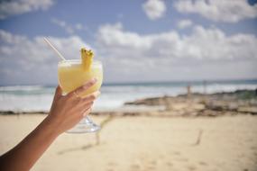 cocktail pina colada in hand on the beach on a blurred background