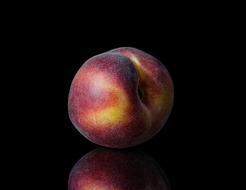 Beautiful and colorful peach, with reflection, at black background