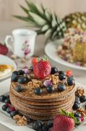 Beautiful pancakes with colorful berries and tea on a table