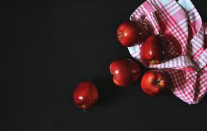 Beautiful, shiny, red apples, on the colorful cloth, at black background