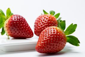 fresh juicy strawberry with green tails on white