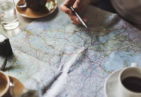 Beautiful and colorful travel map under the cups with coffee