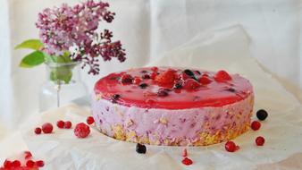 Beautiful and colorful quark cake, with the berries and jelly, near the colorful and beautiful flowers