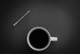 Black and white photo with the top view of a cup of liquid and pencil, on a surface