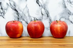 Beautiful red, yellow and orange apples on the wooden surface near the black and white wall