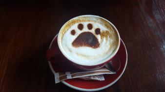 Cup of coffee, with the beautiful drawing of the paw, with the sugar packs on the saucer
