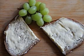 Beautiful, brown bread with the butter and beautiful green grapes, on the wooden board