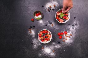 Person, making beautiful summer dessert with berries in the kitchen