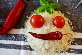 Beautiful face with red pepper, tomatoes and basil on the white rice