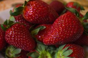 Beautiful, shiny, red strawberries with green leaves, in the pile