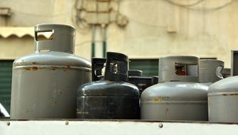 Shiny, grey and black gas bottles, near the wall