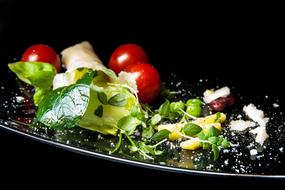 salad with tomatoes, Japanese spinach and parmesan on a shiny plate