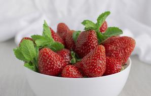ripe strawberries with mint in a white plate
