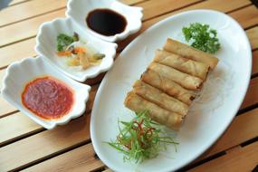 Beautiful Chinese spring rolls, sauces and vegetables, on the plates