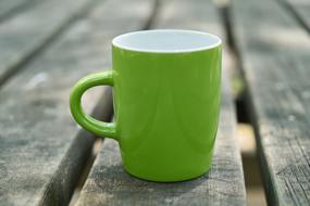 green cup on the garden table close-up on blurred background