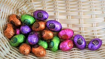 Beautiful, shiny, colorful, chocolate Easter eggs in the wicker basket