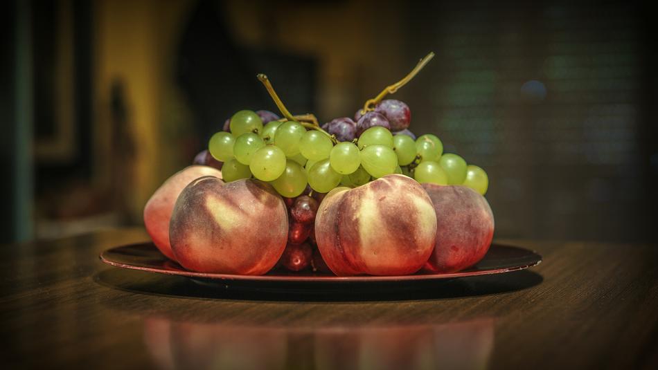 Beautiful, green and purple grapes, on the colorful and beautiful peaches, on the plate