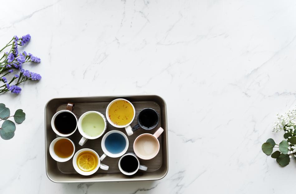 multicolored drinks in cups on a tray on a white table