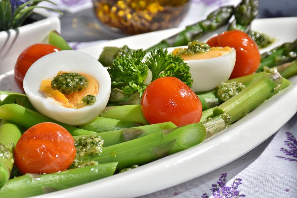 Beautiful and colorful plate with asparagus, tomatoes, eggs and greenery with pesto