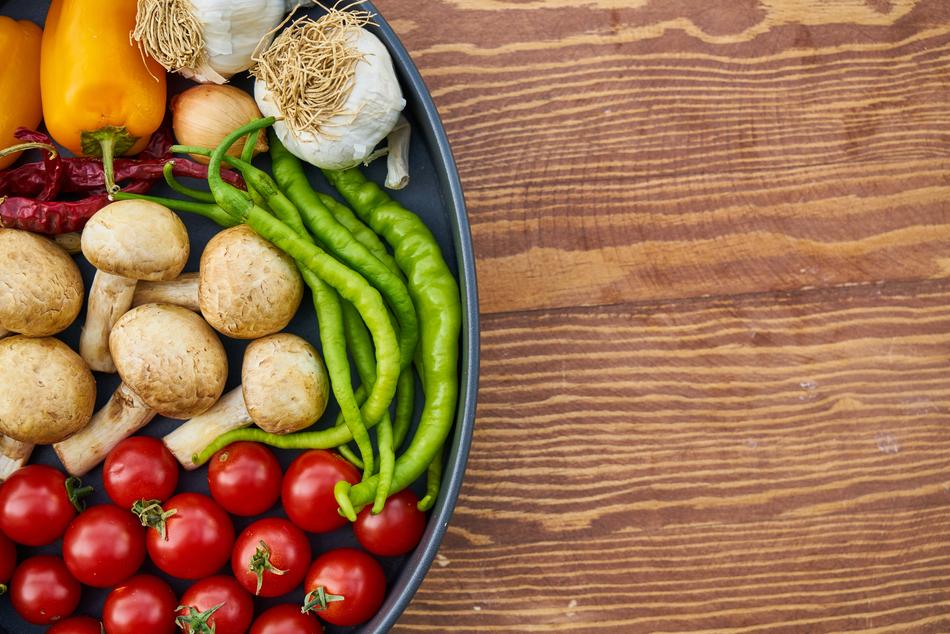 Beautiful and colorful plate with tomatoes, green and red peppers, mushrooms, garlic and onion, on the wooden table