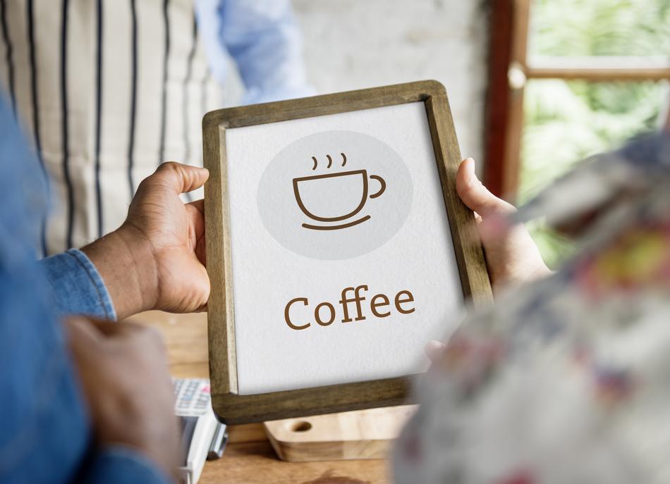 persons holding board with coffee in cup drawing