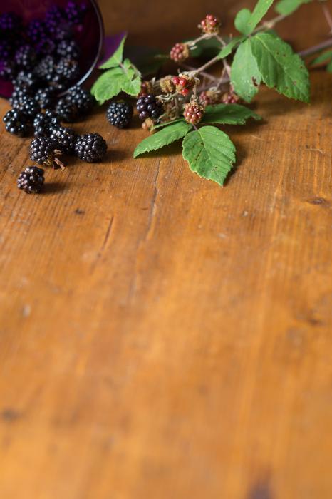 Beautiful and colorful berries with green leaves, on the wooden surface