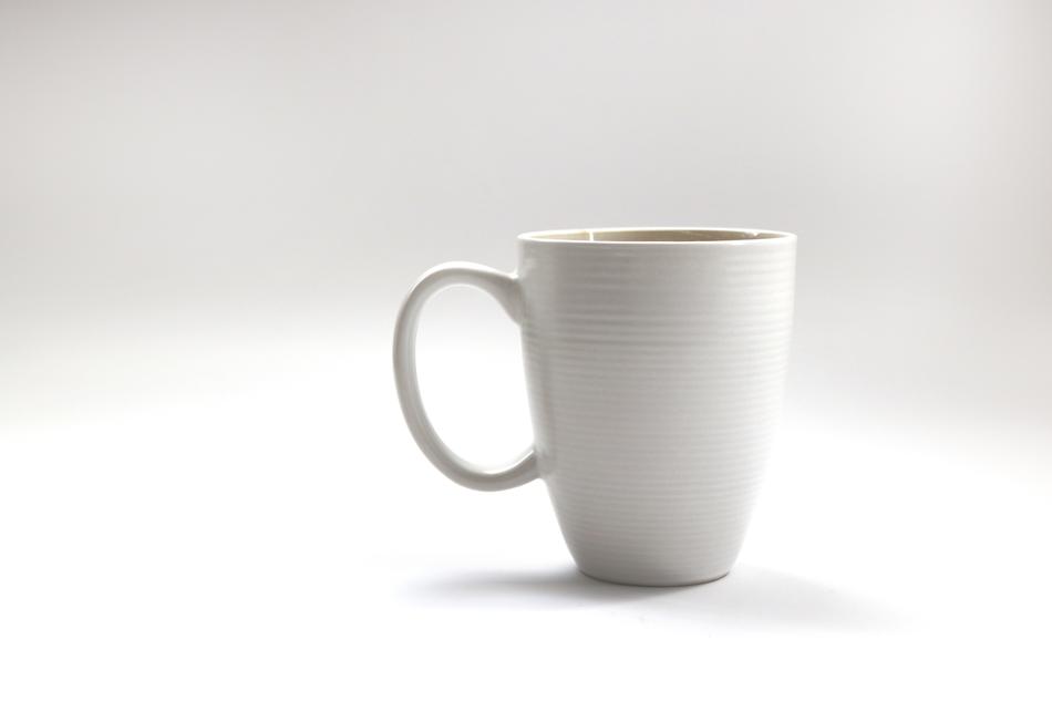 Beautiful, shiny, white mug of coffee, with the shadow, on the white surface